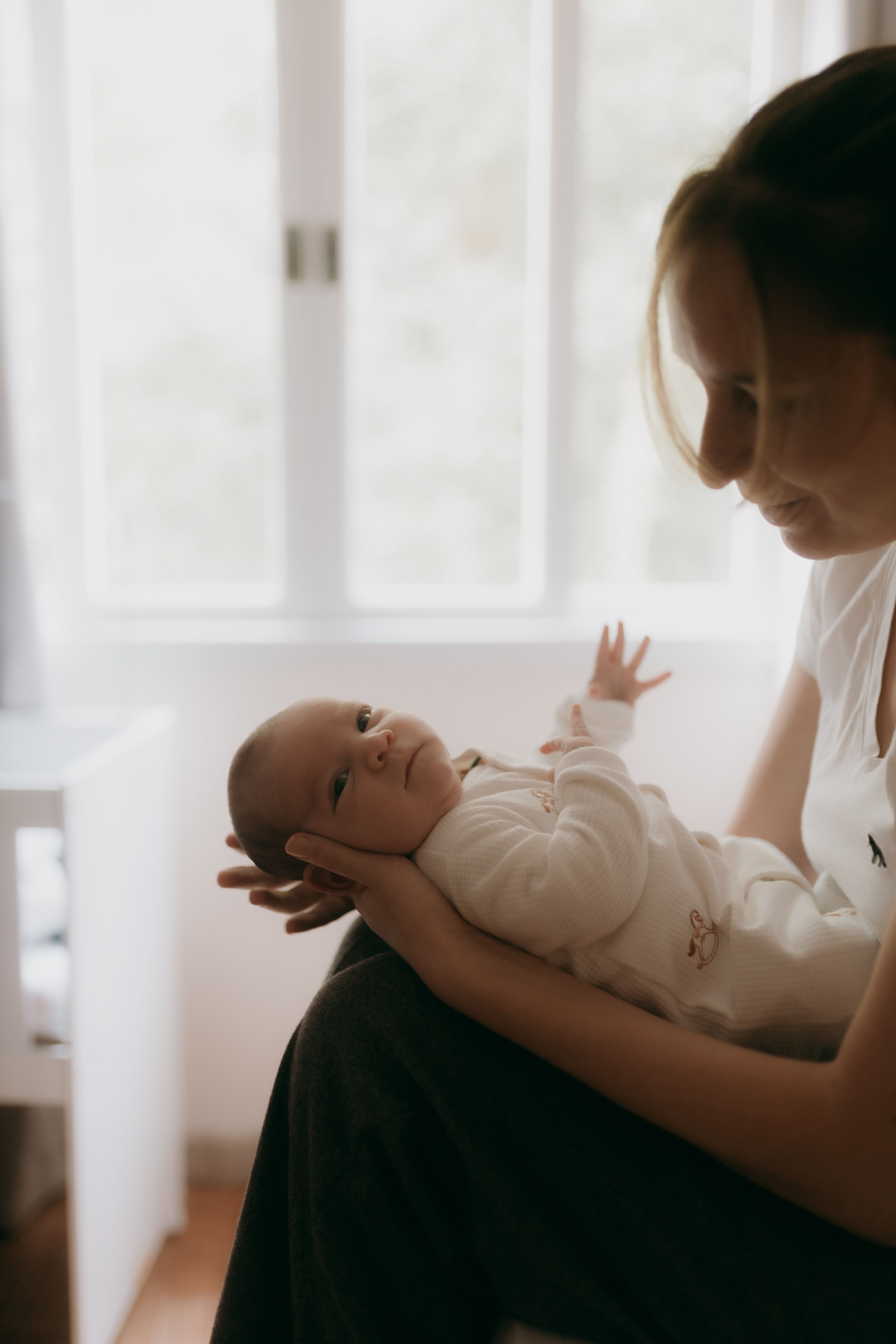 Mother gazing at her newborn by the window